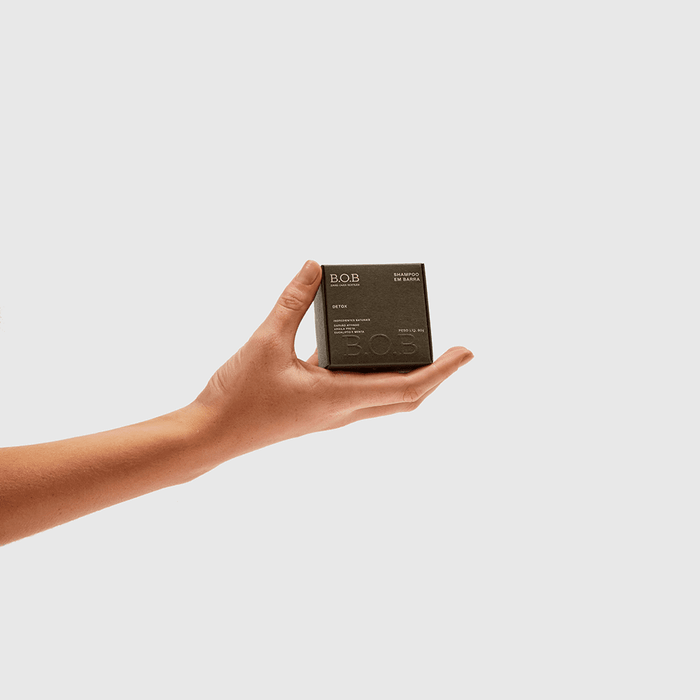Mão segurando embalagem de Shampoo Detox B.O.B